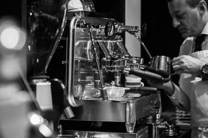 Barista pouring milk at the espresso machine